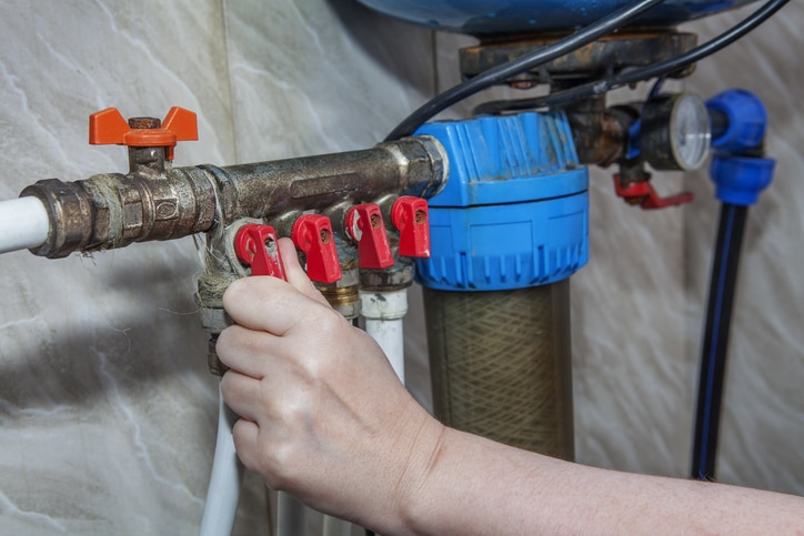 Plumbing manifold system tubing for house water distribution, control valves home water pipe, close-up human hand opening valve.